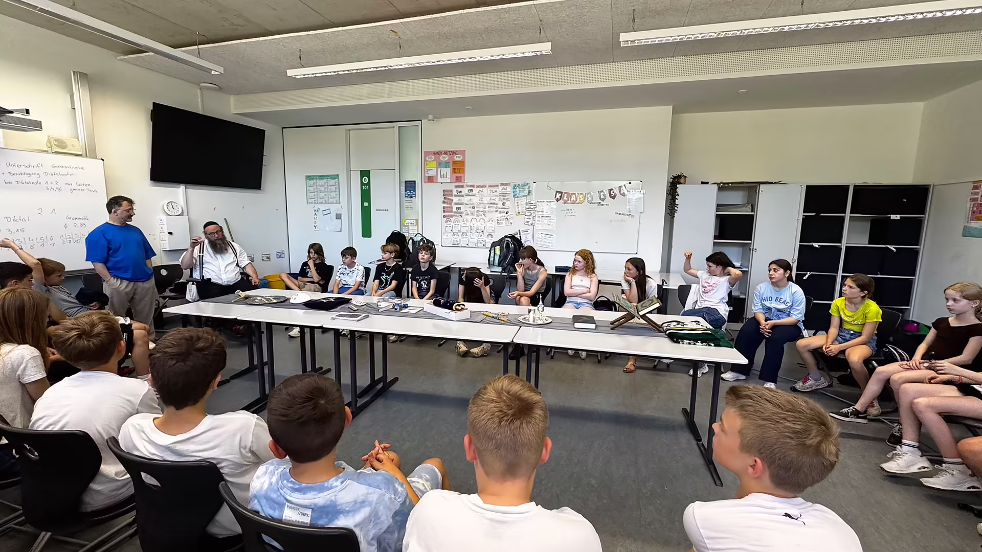 Schülerinnen und Schüler sitzen im Stuhlkreis und hören den Referenten des Maimonides Bildungswerks zu