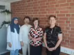 Gruppenfoto von vier Personen vor einer Backsteinwand