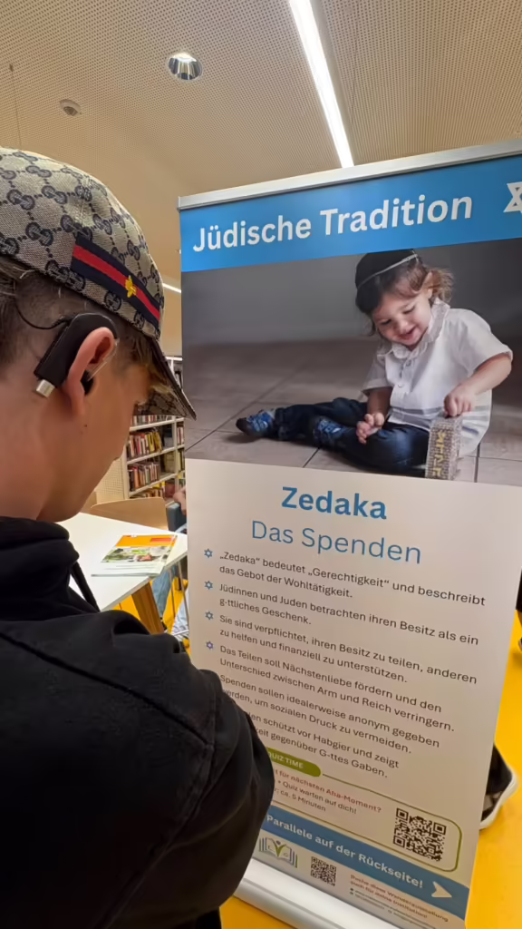 Schüler vor dem Banner Zedaka, Das Spenden, aus der jüdischen Tradition