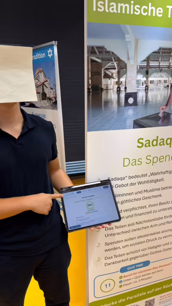 Schüler zeigt auf dem Tablet 100 Prozent im Quiz zur Station Zedaka und Sadaqa