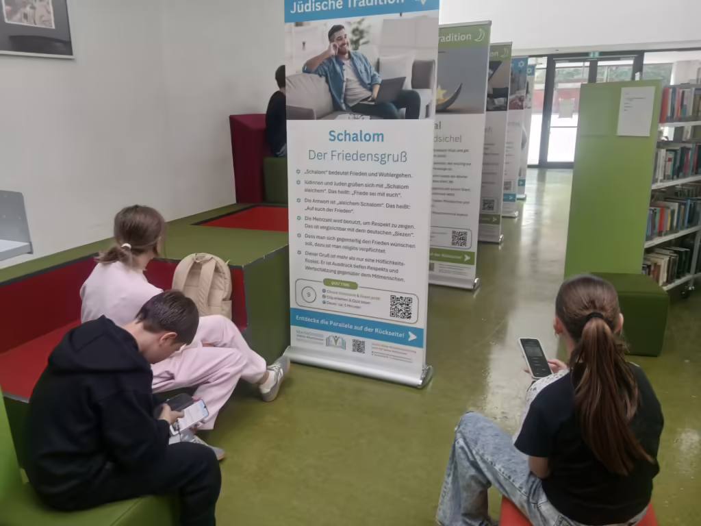 Jugendliche sitzen vor den Bannern auf dem Boden und bearbeiten das Quiz