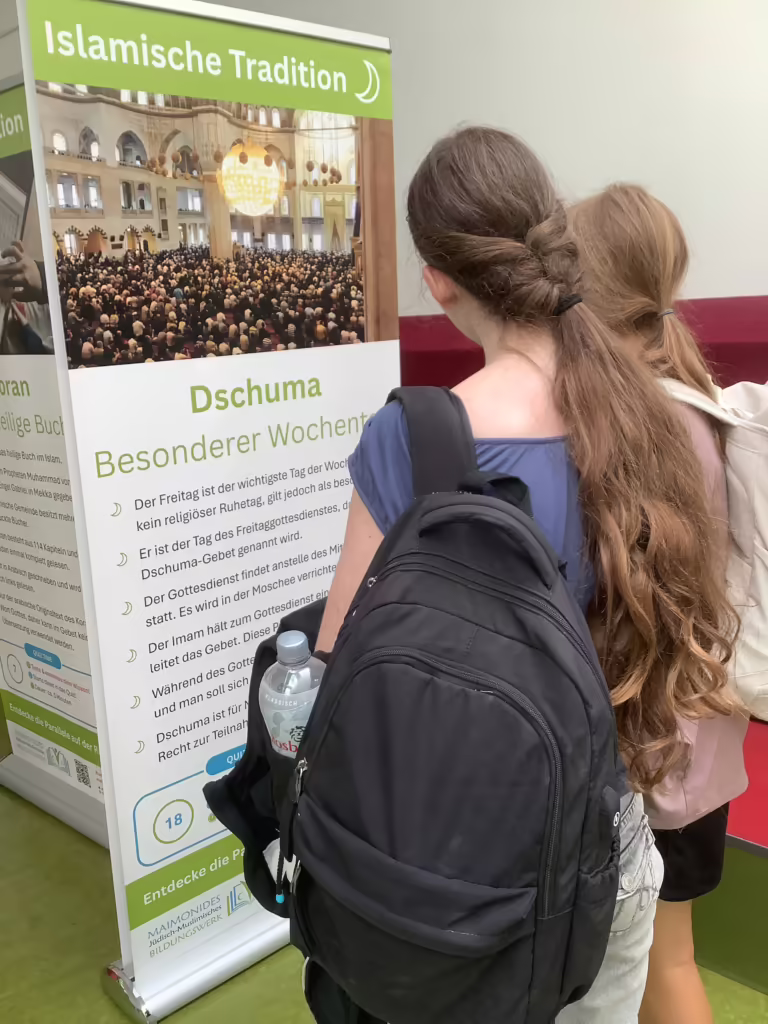 Schülerinnen vor dem Banner Dschuma, Besonderer Wochentag, aus der islamischen Tradition