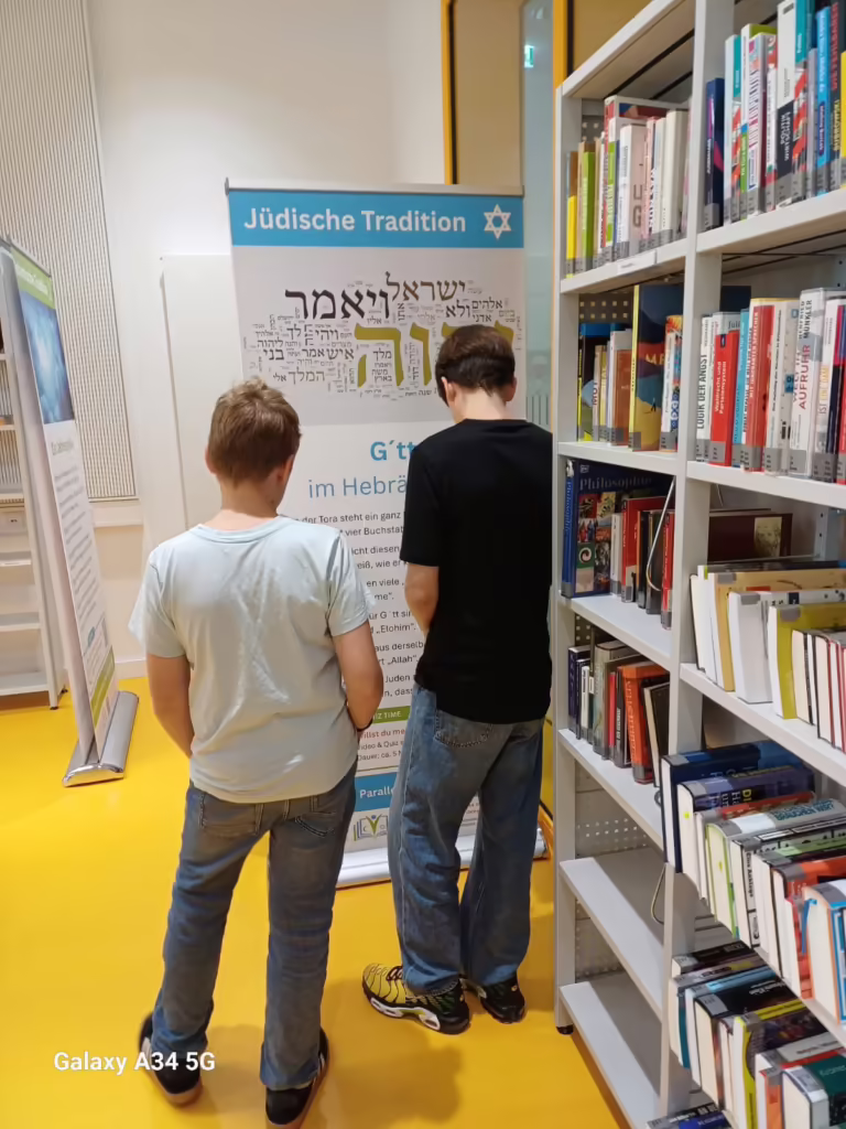 Zwei Schüler lesen ein Banner der jüdischen Tradition in der Schulbibliothek