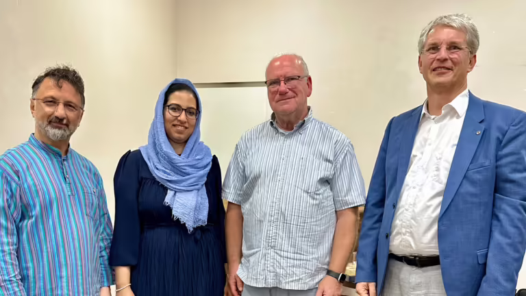 Mustafa Cimşit, Misbah Arshad, Manfred Levy und Dekan Olliver Zobel stehen nebeneinander in einem hellen Raum und lächeln in die Kamera