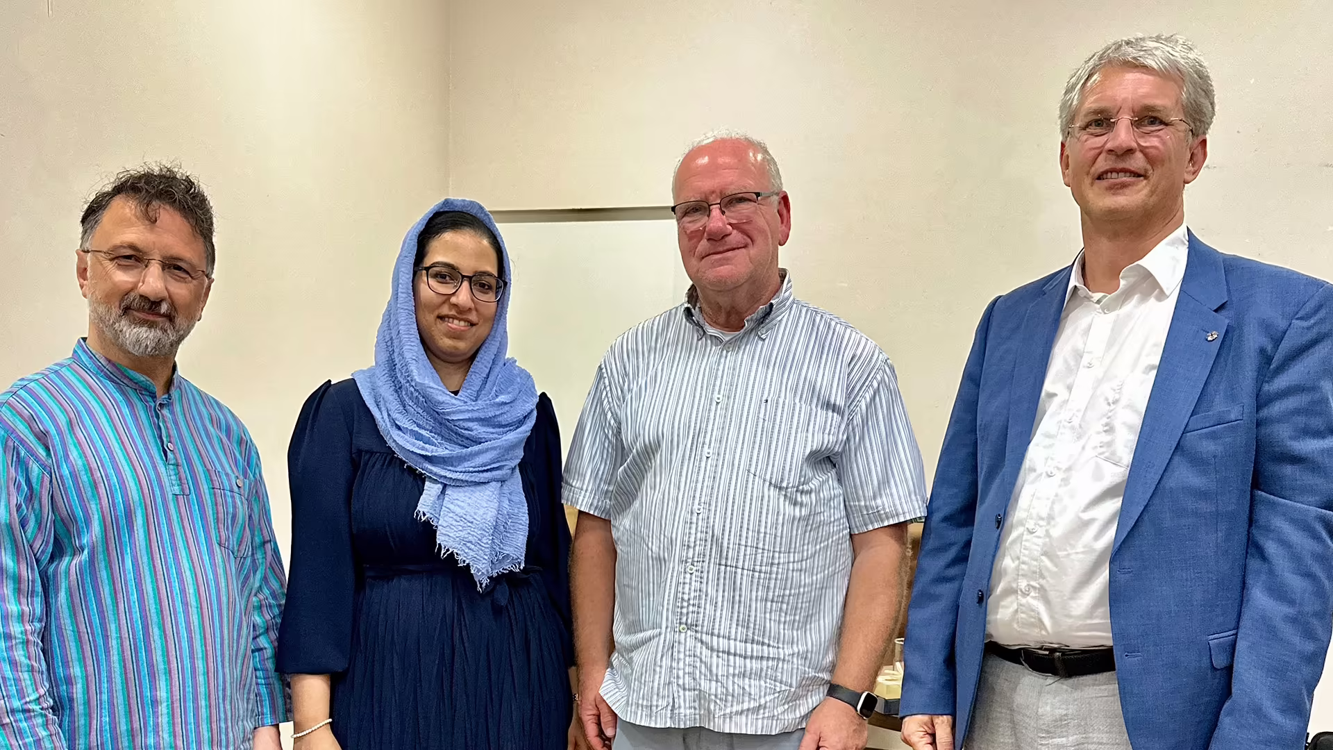 Mustafa Cimşit, Misbah Arshad, Manfred Levy und Dekan Olliver Zobel stehen nebeneinander in einem hellen Raum und lächeln in die Kamera