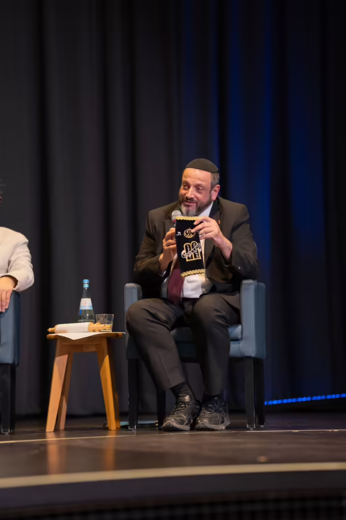 Ein Podiumsgast zeigt beim Ingelheimer Buber Diskurs ein Buch